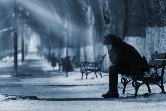 Sad woman sitting on a bench in winter time.