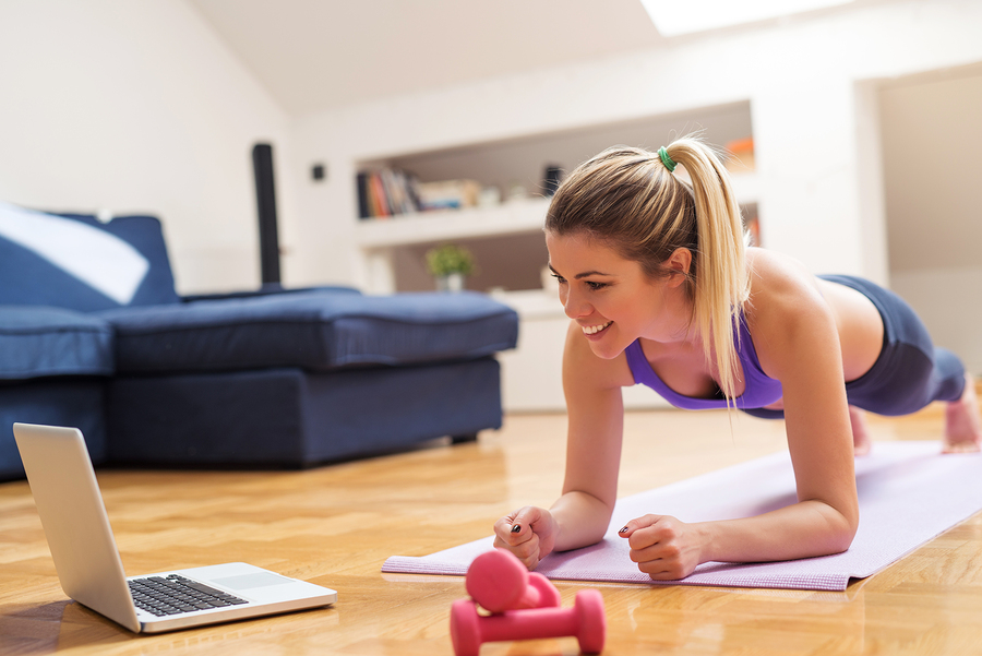 Young girl looking at laptop and doing exercises at home. Young girl looking at laptop and doing exercises at home.