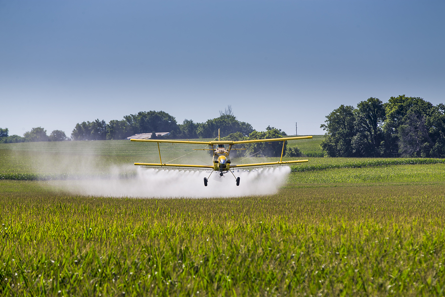 A crop duster applies chemicals to a field of vegetation. A crop duster applies chemicals to a field of vegetation.